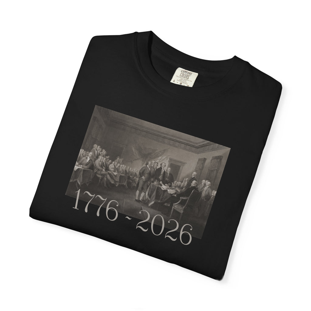 Folded Black Comfort Colors t-shirt with a printed design of Trumbull's  'Declaration of Independence' painting with '1776-2026' in overlapping revolutionary era text
