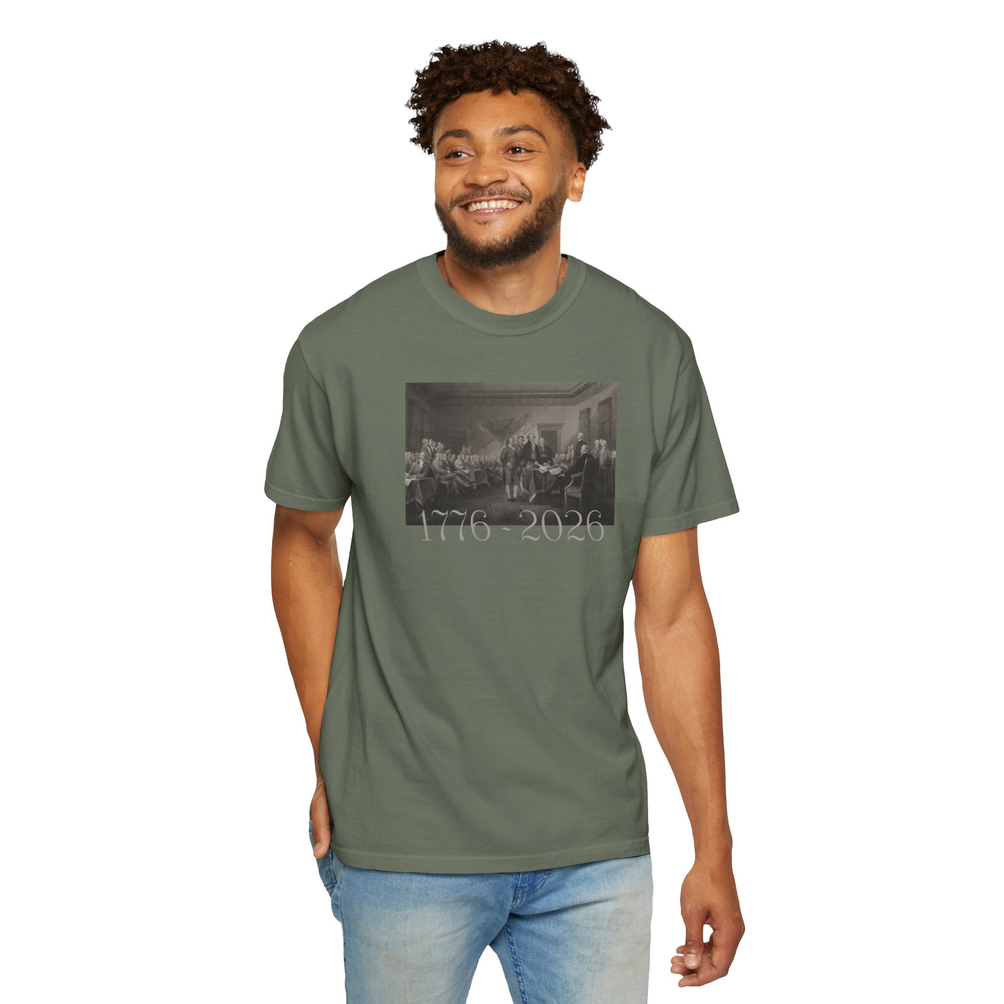 Smiling man wearing a Moss Comfort Colors t-shirt with a printed design of Trumbull's  'Declaration of Independence' painting with '1776-2026' in overlapping revolutionary era text