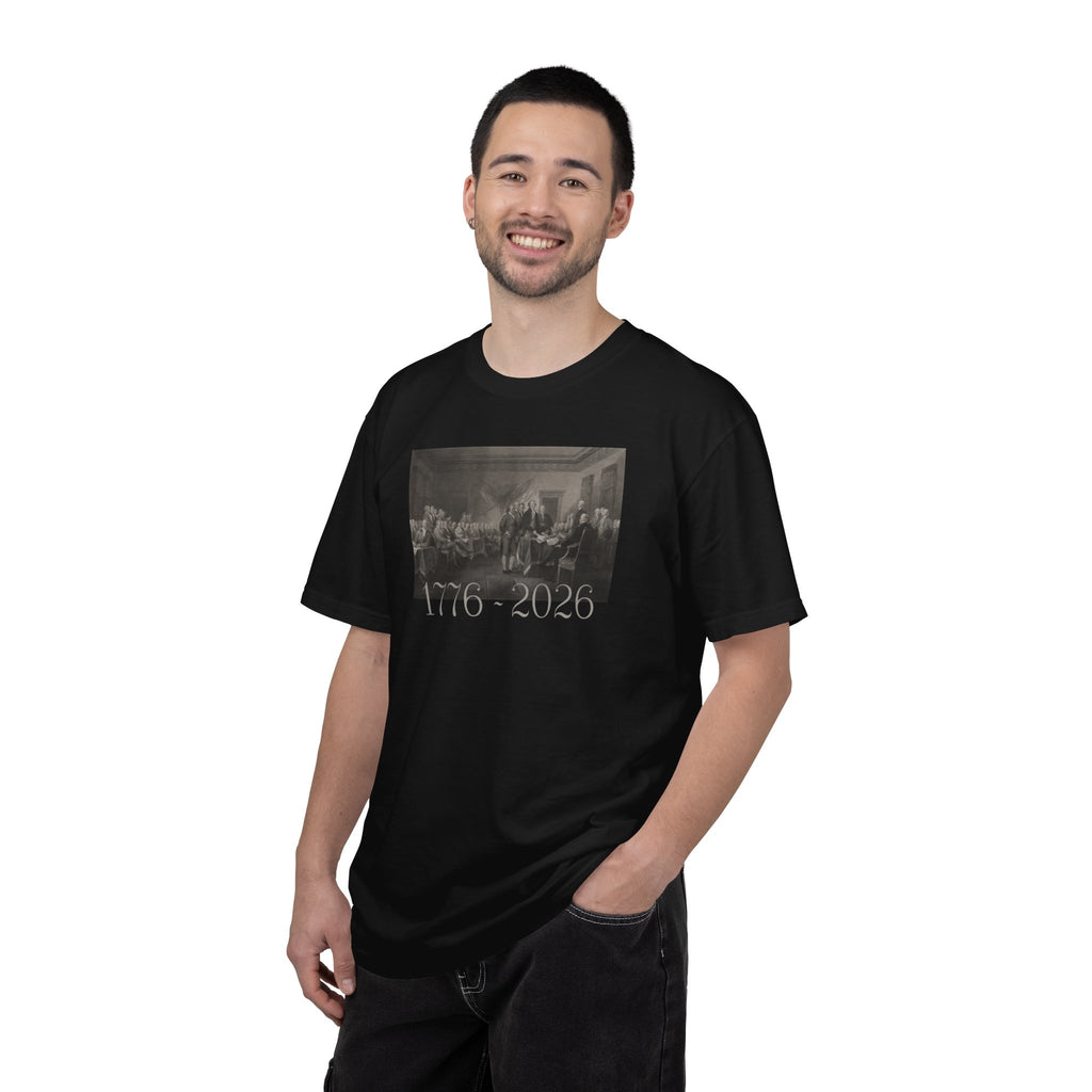 Man wearing a Black Comfort Colors t-shirt with a printed design of Trumbull's  'Declaration of Independence' painting with '1776-2026' in overlapping revolutionary era text
