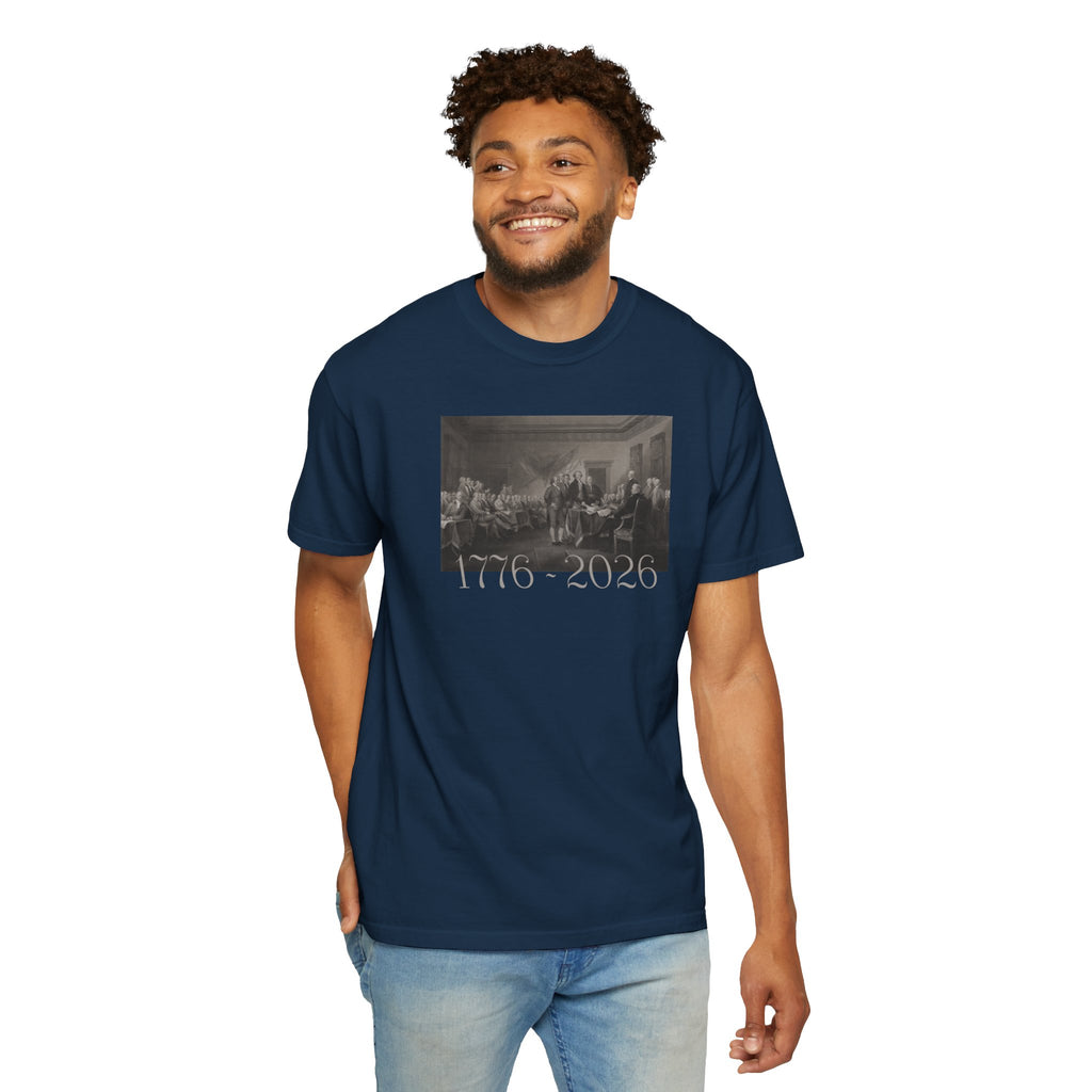 Smiling man wearing a True Navy Comfort Colors t-shirt with a printed design of Trumbull's  'Declaration of Independence' painting with '1776-2026' in overlapping revolutionary era text