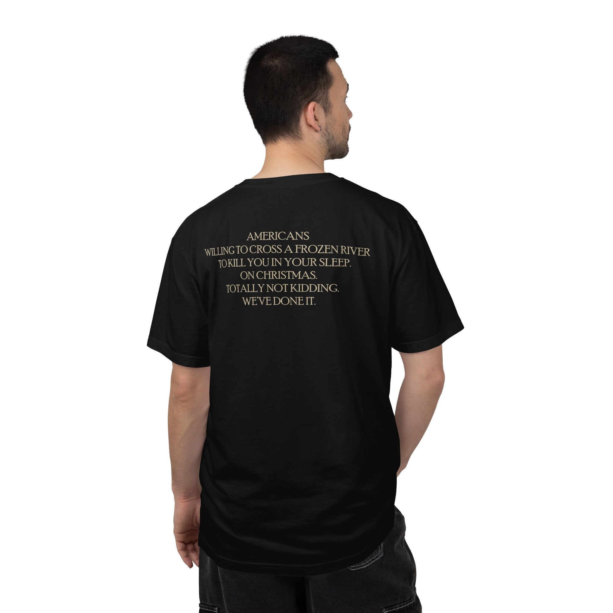 Back view of male model wearing America's First Christmas meme t-shirt with 'AMERICANS Willing to cross a frozen river to kill you in your sleep. On Christmas.' quote. Black