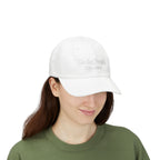 Woman wearing a white cap with embroidered "We the People 1776-2026" against a white background
