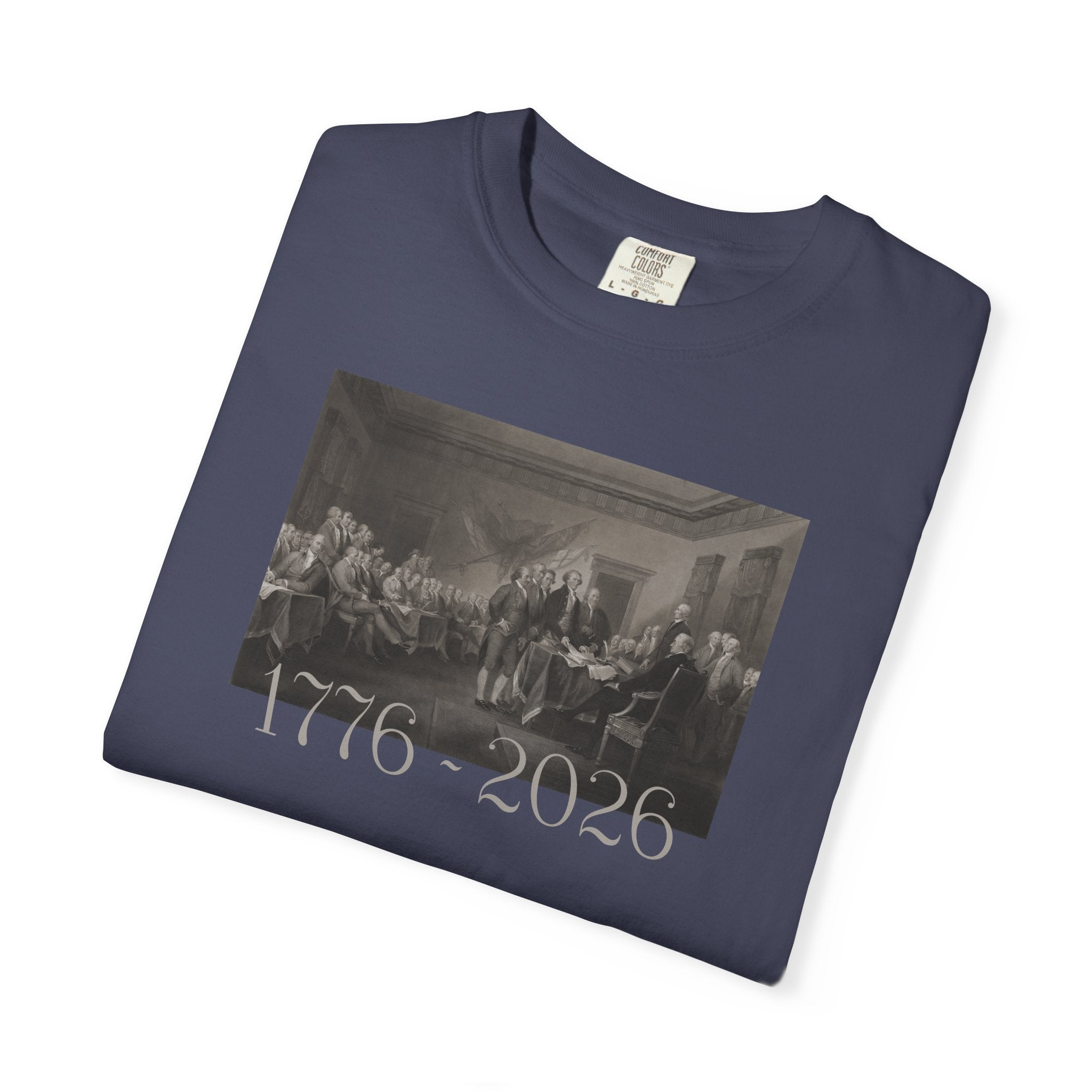 Folded Denim Comfort Colors t-shirt with a printed design of Trumbull's  'Declaration of Independence' painting with '1776-2026' in overlapping revolutionary era text