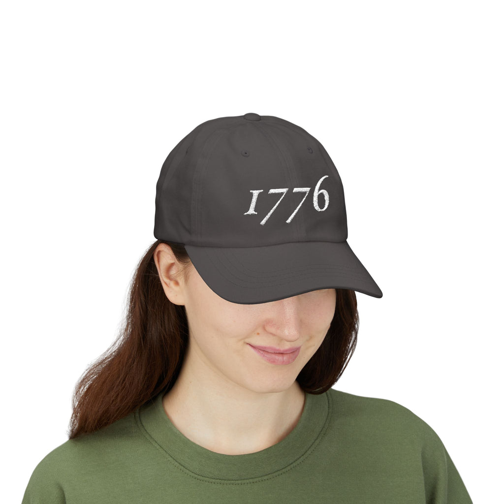 Front view of woman wearing a Dark Grey dad cap embroidered with '1776'