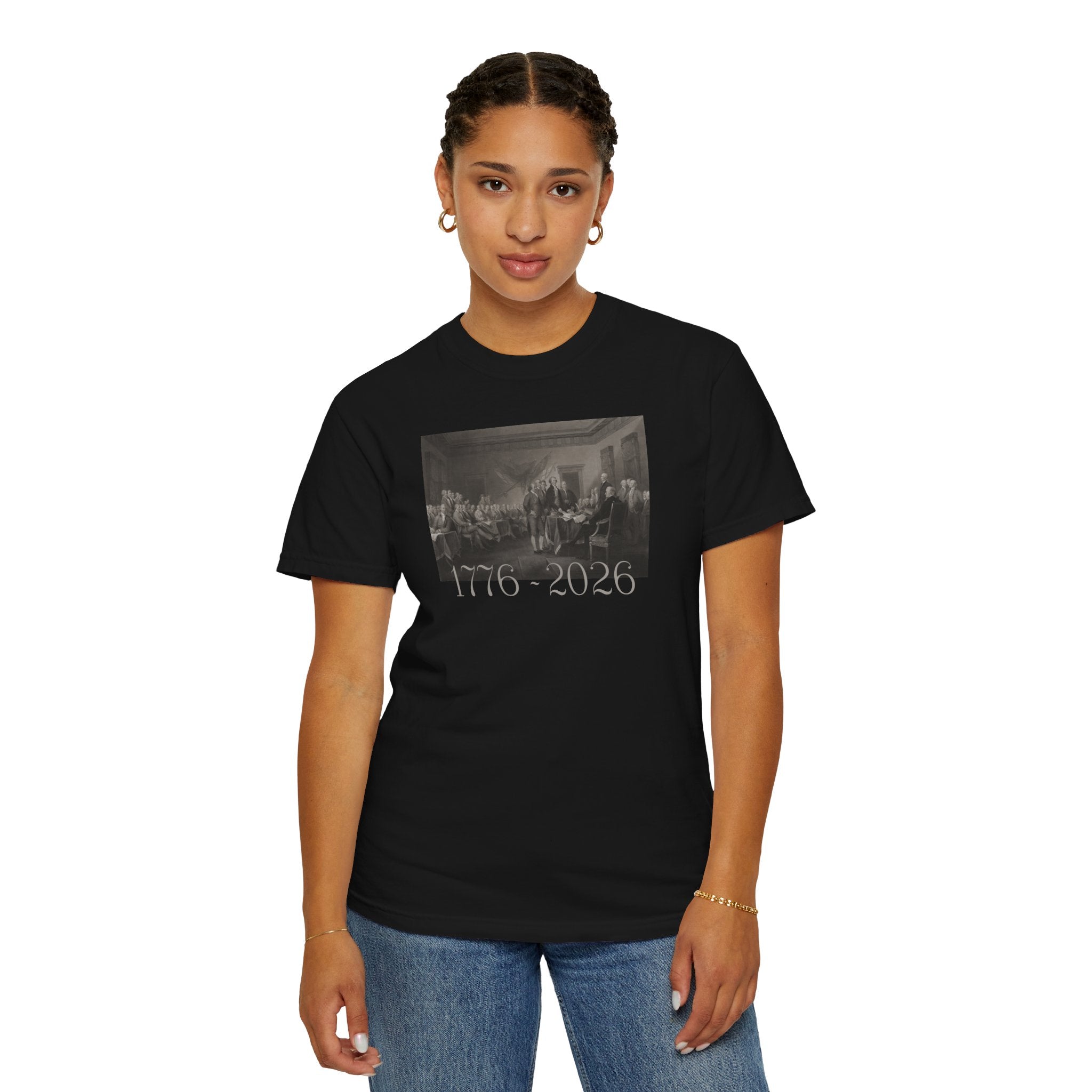 Woman wearing a Black Comfort Colors t-shirt with a printed design of Trumbull's  'Declaration of Independence' painting with '1776-2026' in overlapping revolutionary era text