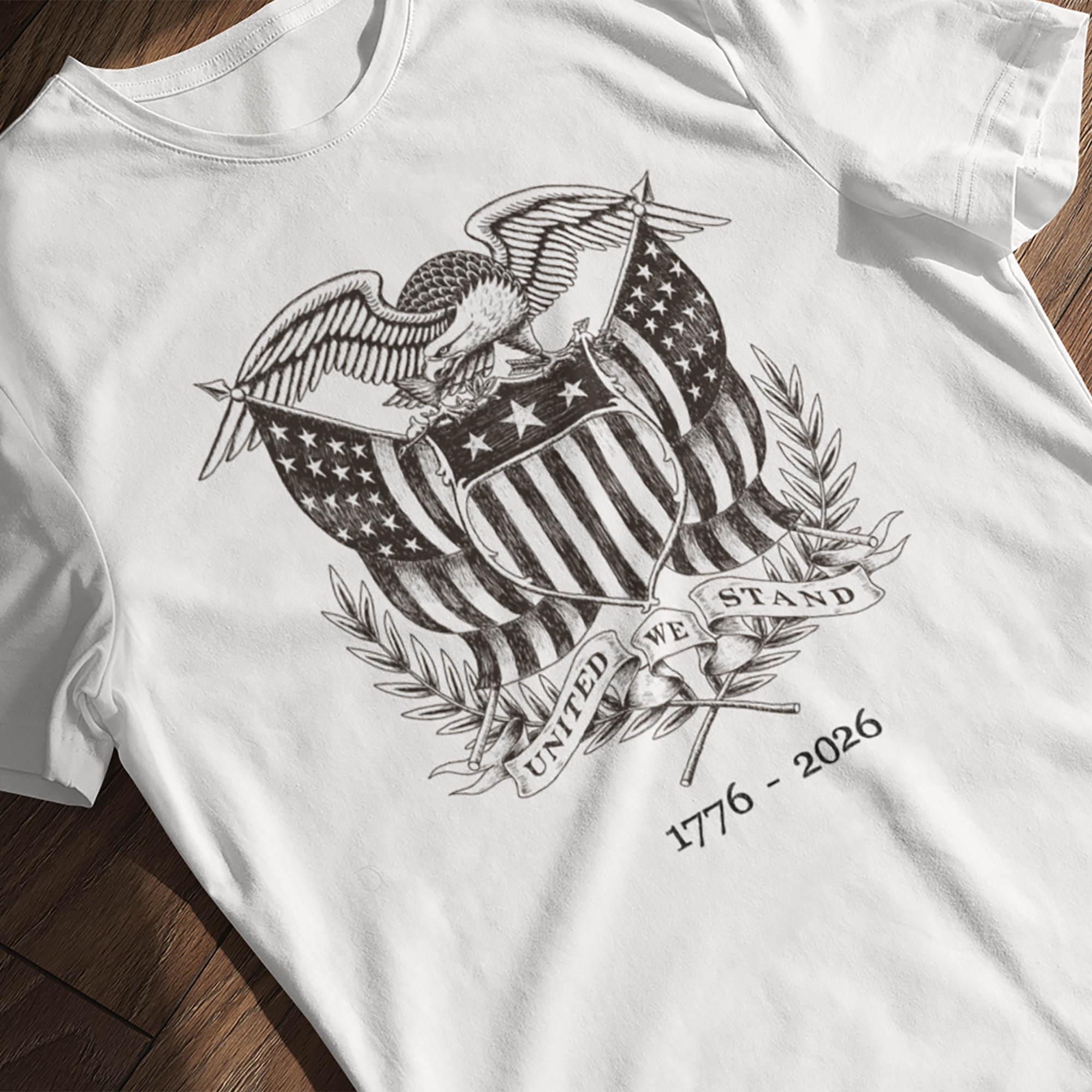 White United We Stand 1776-2026 t-shirt with black graphic design on a wooden surface