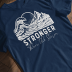 Stronger Than The Storm Christian t-shirt, mountain wave sun design, laying flat on a wooden background
