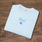 'Blessed Are the Peacemakers' Christian t-shirt embroidered with cornflower blue thread, folded, laying on a wooden surface