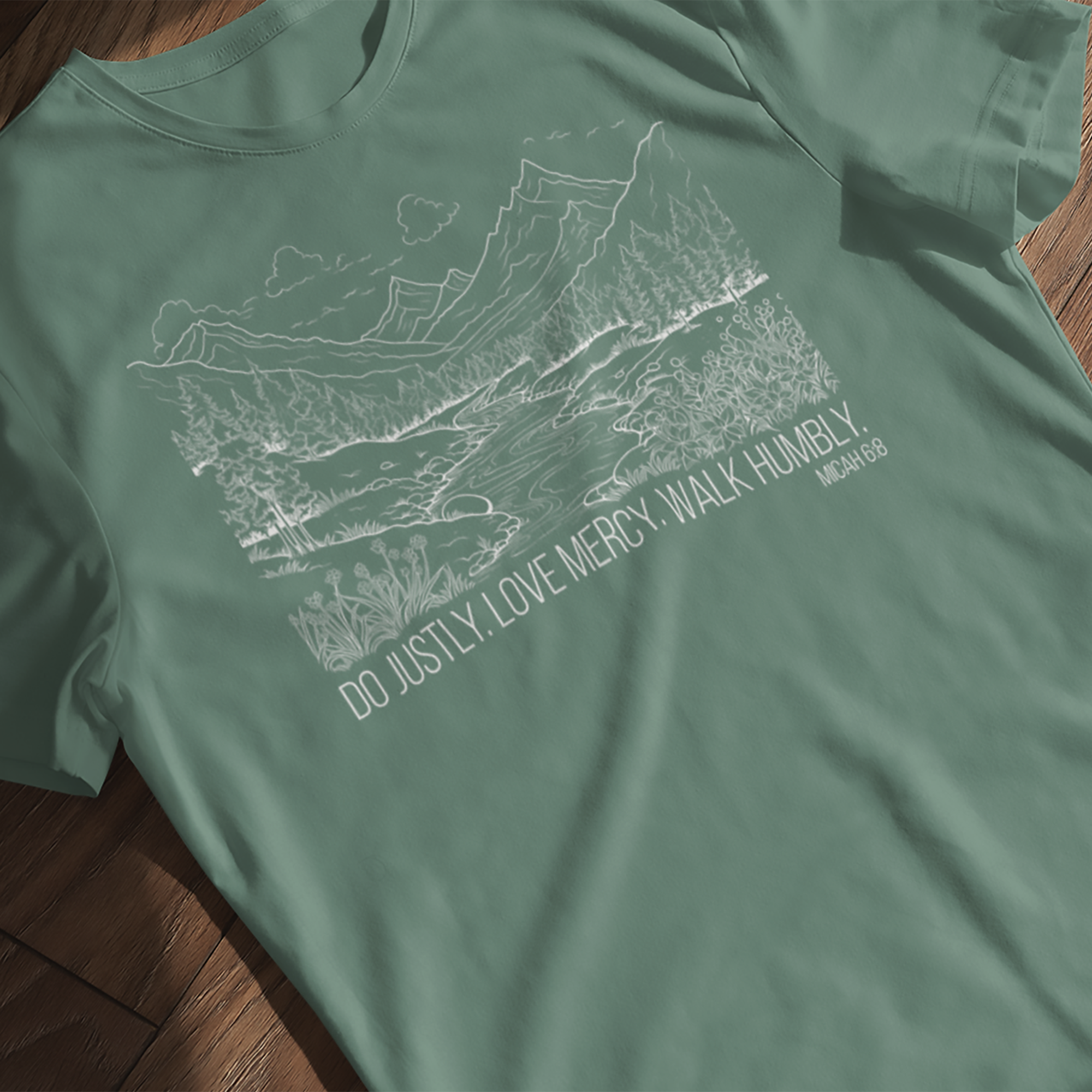Micah 6:8 Do Justly Love Mercy Walk Humbly t-shirt, mountain-river line drawing laying flat on a wooden surface