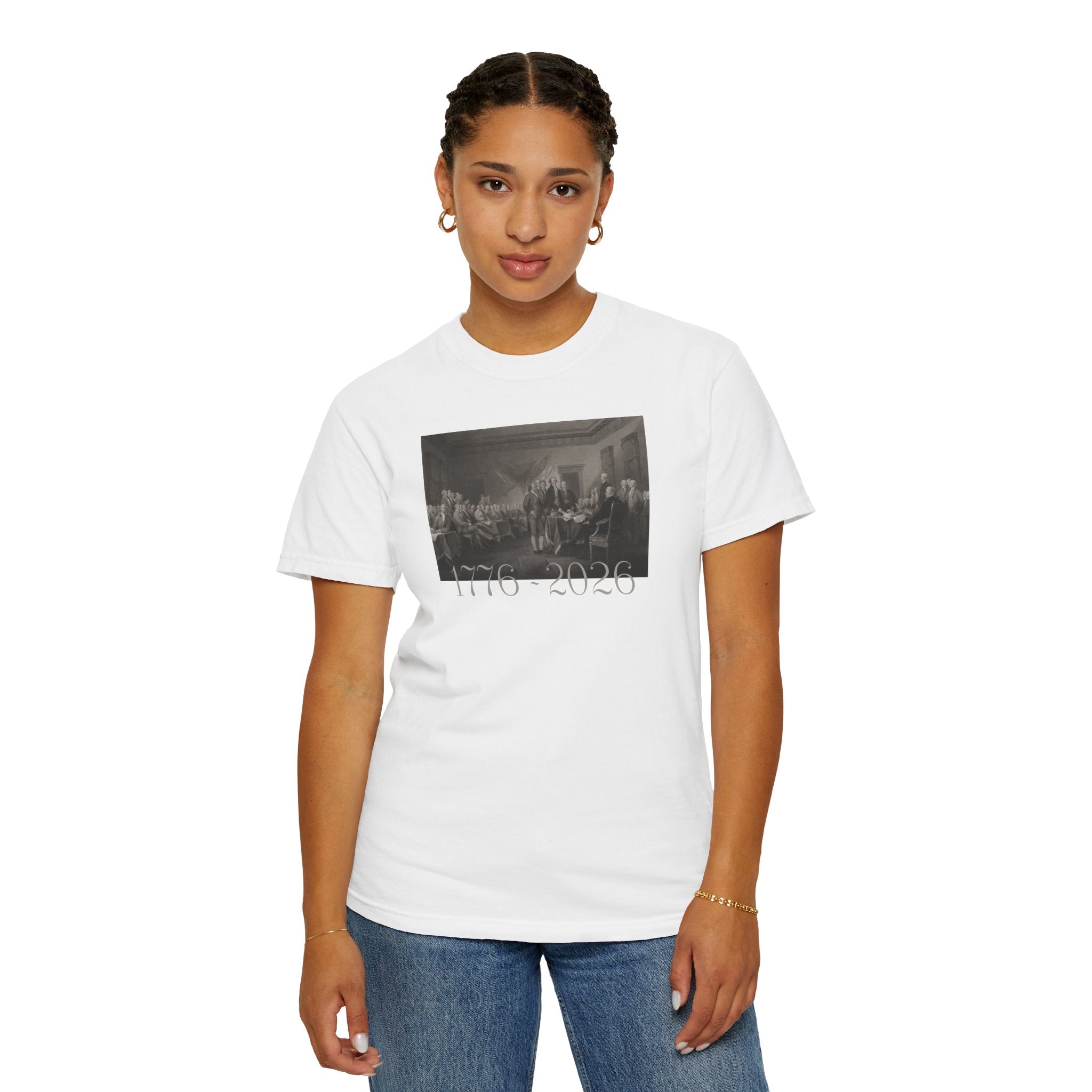 Woman wearing a White Comfort Colors t-shirt with a printed design of Trumbull's  'Declaration of Independence' painting with '1776-2026' in overlapping revolutionary era text