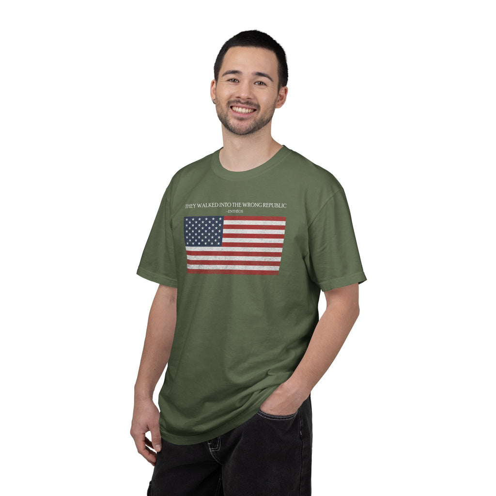 Smiling man wearing a Sage Comfort Colors t-shirt with distressed American flag graphic and 'They Walked Into the Wrong Republic' quote from Entheos