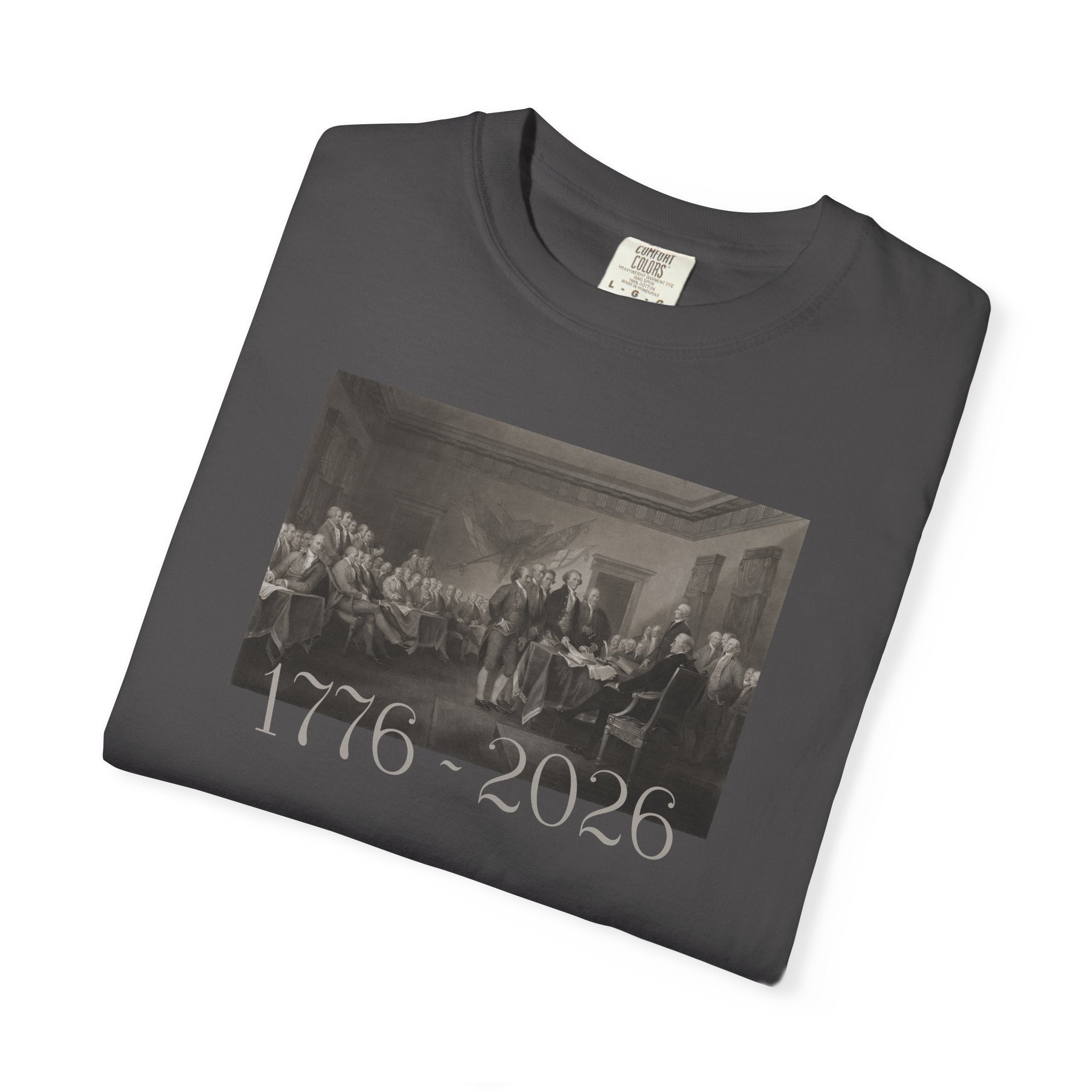 Folded Graphite Comfort Colors t-shirt with a printed design of Trumbull's  'Declaration of Independence' painting with '1776-2026' in overlapping revolutionary era text
