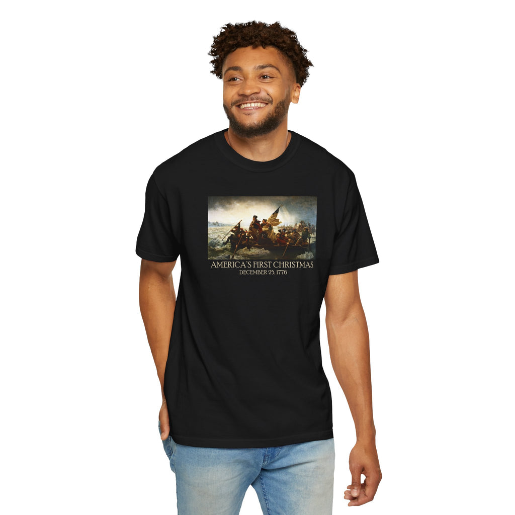 Man wearing a black Comfort Colors t-shirt with print of Emanuel Leutze’s 'Washington Crossing the Delaware' with 'America's First Christmas December 25, 1776' printed below 
