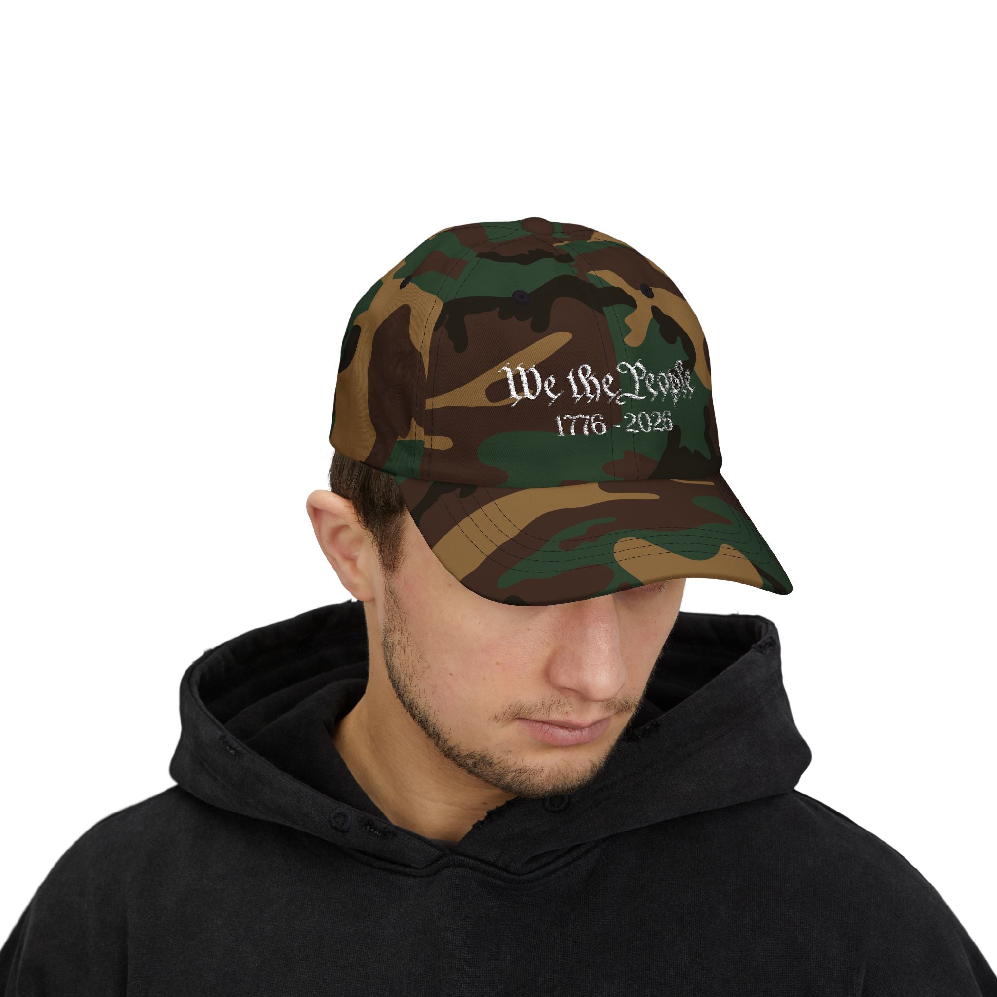 Man wearing a Green Camo cap with embroidered "We the People 1776-2026" 