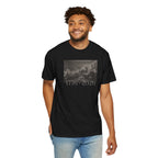 Smiling man wearing a Black Comfort Colors t-shirt with a printed design of Trumbull's  'Declaration of Independence' painting with '1776-2026' in overlapping revolutionary era text