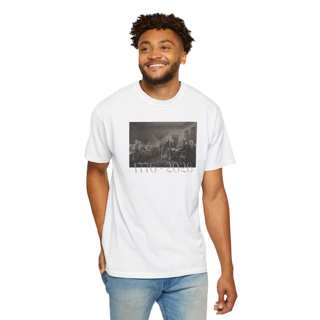Smiling man wearing a White Comfort Colors t-shirt with a printed design of Trumbull's  'Declaration of Independence' painting with '1776-2026' in overlapping revolutionary era text