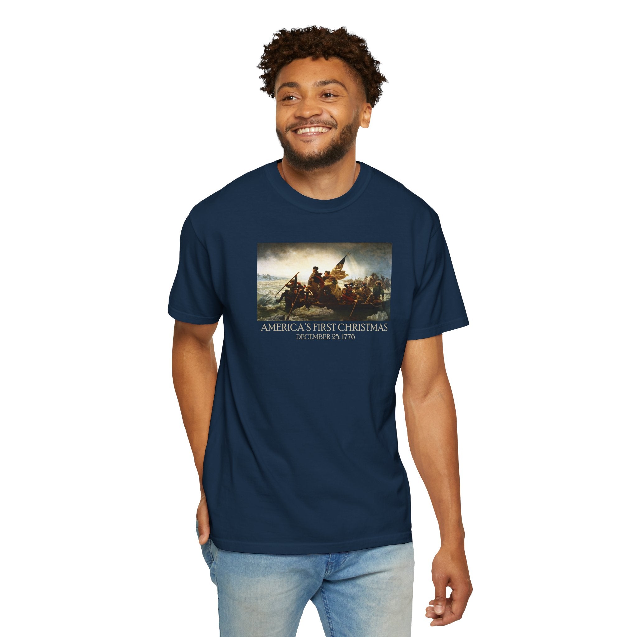 Man wearing a true navy Comfort Colors t-shirt with print of Emanuel Leutze’s 'Washington Crossing the Delaware' with 'America's First Christmas December 25, 1776' printed below 
