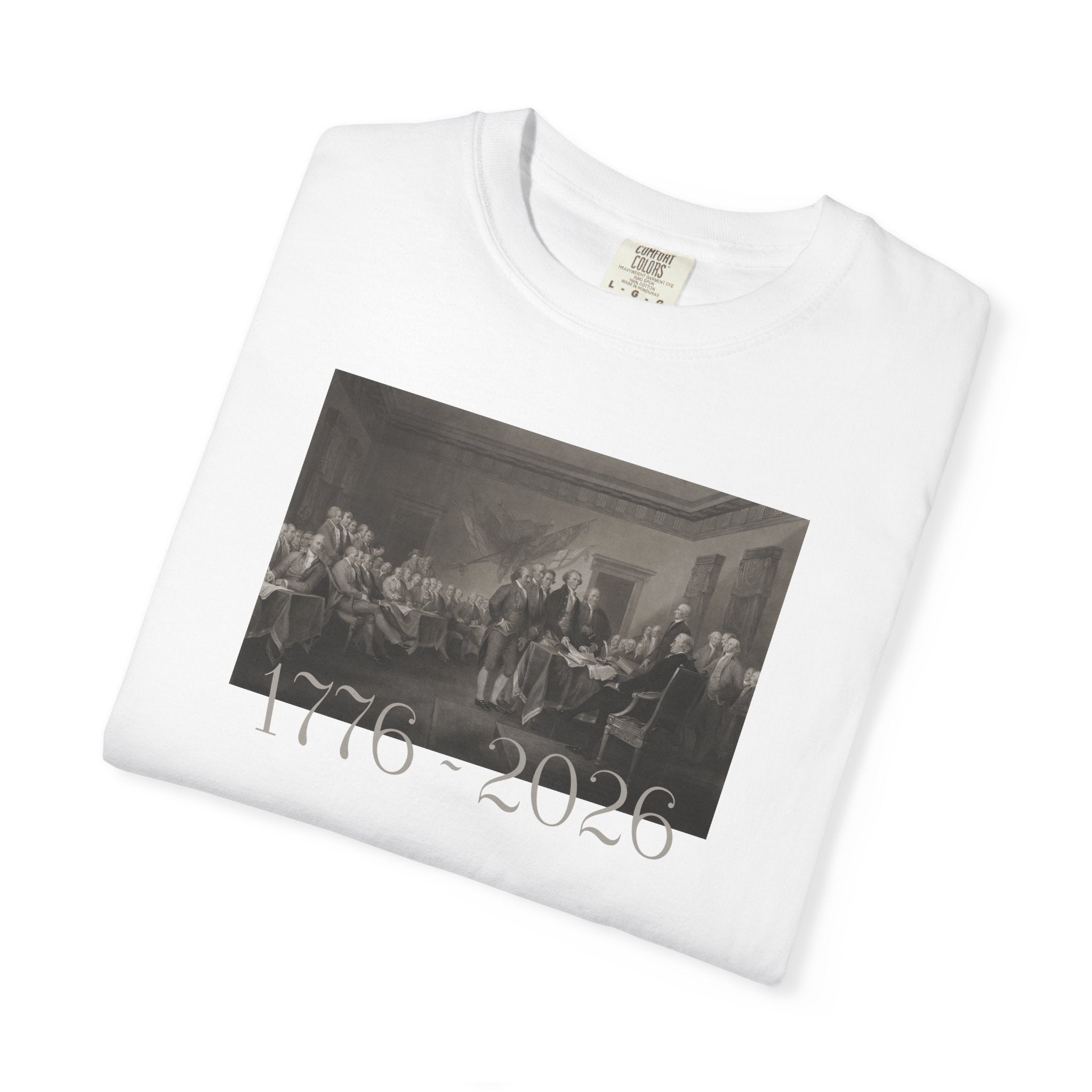 Folded White Comfort Colors t-shirt with a printed design of Trumbull's  'Declaration of Independence' painting with '1776-2026' in overlapping revolutionary era text