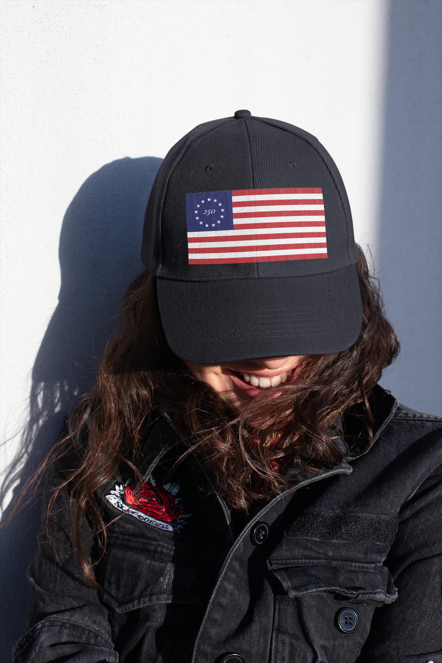 Model wearing a black cap embroidered with Betsy Ross flag