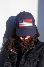Model wearing a navy cap embroidered with Betsy Ross flag