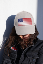 Model wearing a stone cap embroidered with Betsy Ross flag