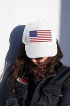 Model wearing a white cap embroidered with Betsy Ross flag