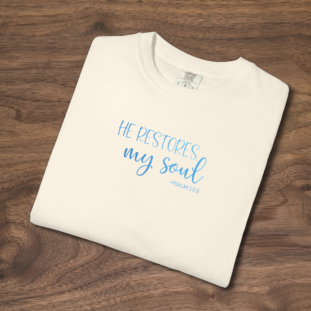 'He Restores My Soul' Christian t-shirt embroidered with cornflower blue thread, Psalm 23:3 design, folded