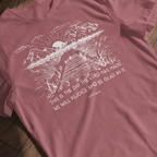 Psalm 118:24 t-shirt with rising sun and water design ("This is the day the Lord has made; we will rejoice and be glad in it) laying flat against a wooden background