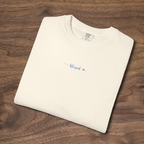 'Blessed' Christian t-shirt embroidered with cornflower blue thread, folded, laying on a wooden surface