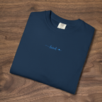 t-shirt with 'loved' plus a tiny heart embroidered with cornflower blue thread, folded, laying on a wooden surface